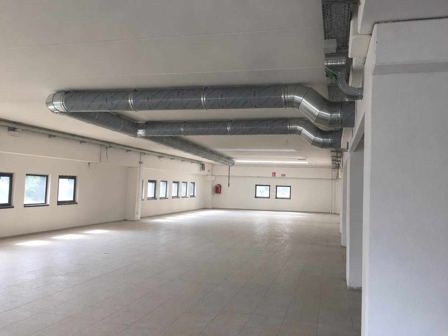 Interno di un grosso magazzino con grandi condotte di ventilazione in acciaio installate sotto la copertura